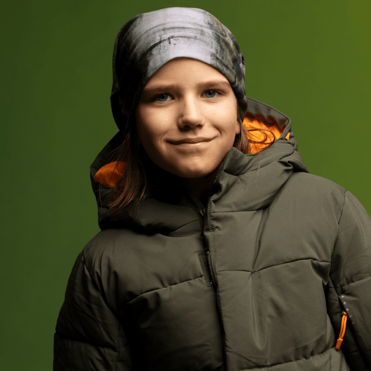 Close-up portrait of a young girl wearing the Wall Multifunctional Tube as a beanie, smiling.