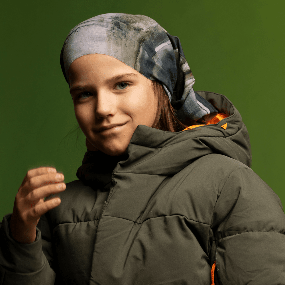 Young girl wearing the Wall Multifunctional Tube as a headband with a green puffer jacket.