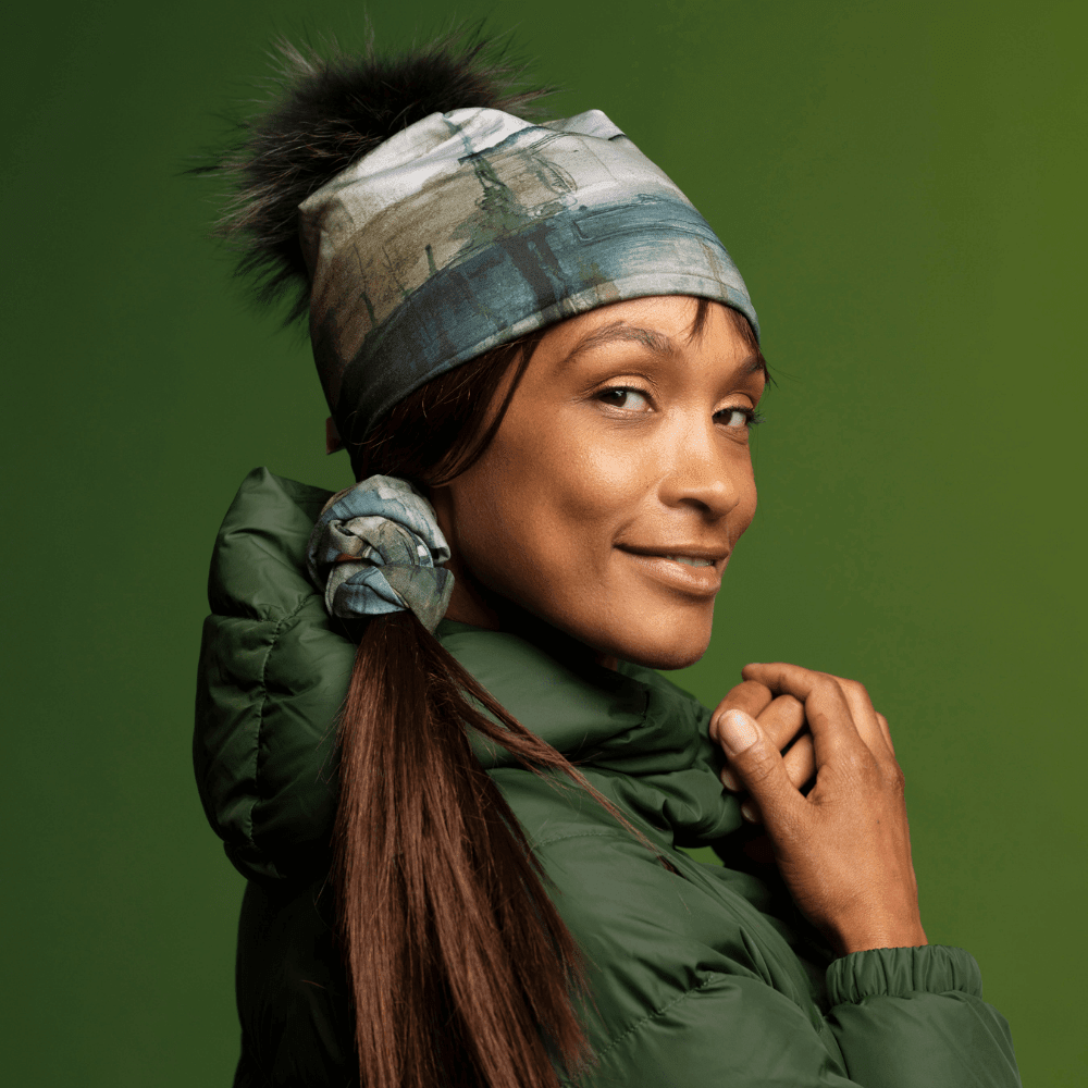 Woman wearing a Wall Beanie and scarf as a hair tie, styled with a green puffer jacket.