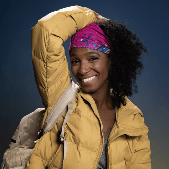 Woman wearing a yellow puffer jacket and the pink abstract print tube as a headband.
