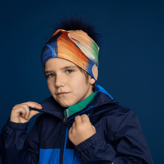 Young boy wearing the Yellow &amp; Blue Beanie with removable navy fur pom, styled with a jacket.