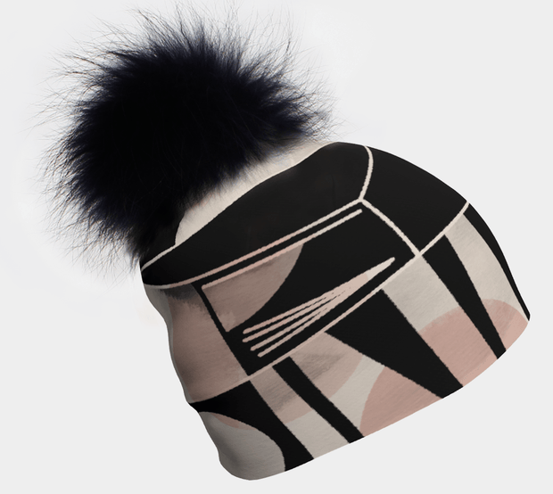 A beanie with a black and pink geometric pattern and a detachable black pompom.