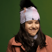 Laughing teenager wearing the Blush and Black Modern Quilt Beanie with Black Pompom by Catherine Parent for the Lalita's Art Shop 25 collection