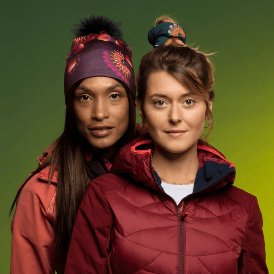 Woman wearing the Sunflower Read Beanie with Black Pompom from Zaire with the friend wearing the Sunflower Green Tube as hair Scrunchie. Lalita&