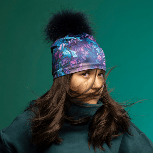 Teenager girl wearing the floral Blue and Purple Wisteria Beanie with Navy Pompom by Claire Anghinolfi for the Lalita's Art Shop 25 collection